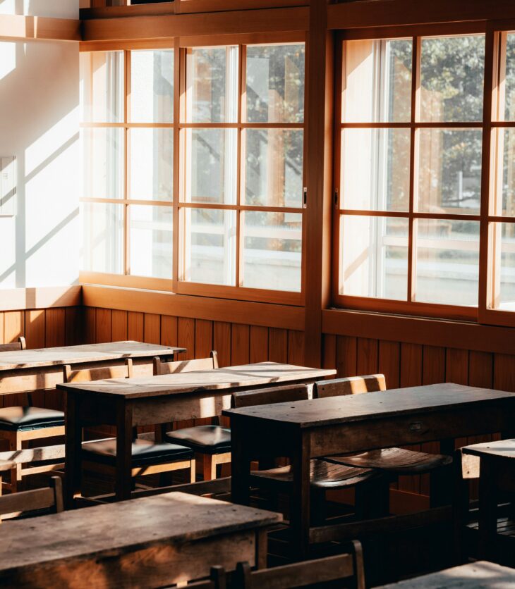 Empty classroom with wooden desks and chairs.